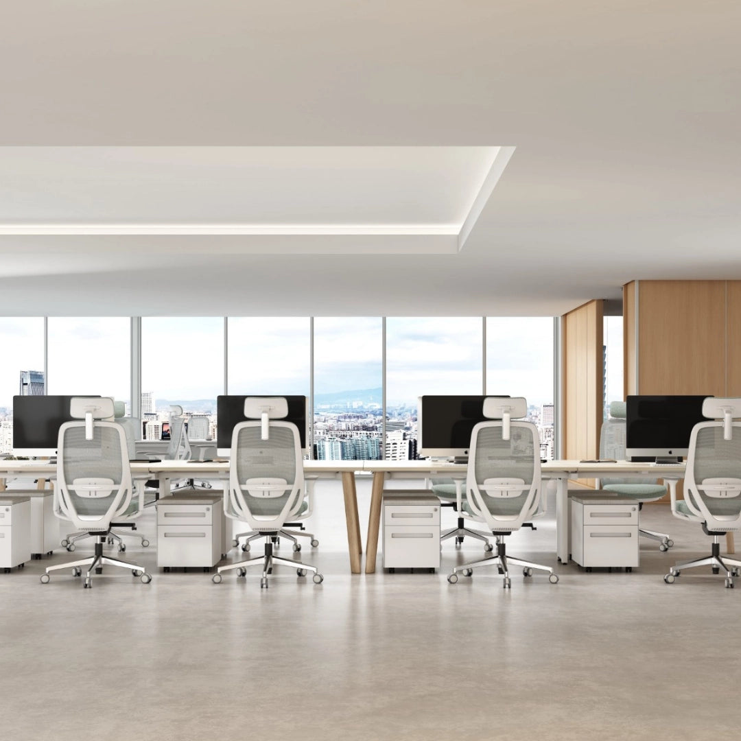 The image features ergonomic office chairs arranged in a modern office setting. The chairs have a sleek design with mesh backs and headrests, promoting comfort and support for long hours of work. The workspace includes desks and computer monitors, with large windows providing a view of the city.