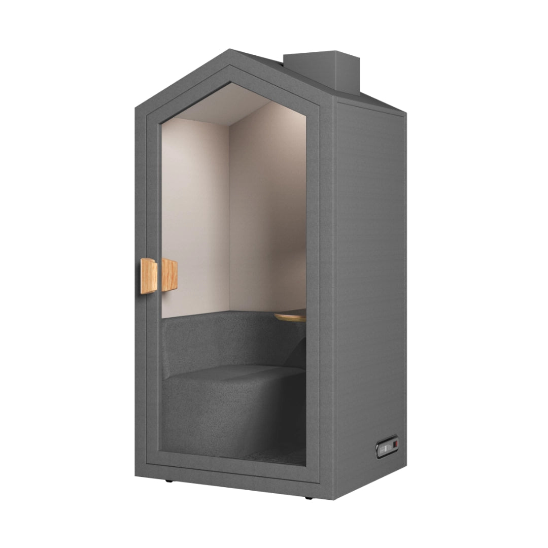 The product is an acoustic meeting pod designed for private discussions in office environments. It features a modern, cottage-like design with a gray exterior and wooden accents. The interior includes a comfortable seating area and a small table, providing a cozy and soundproof space for meetings or calls.