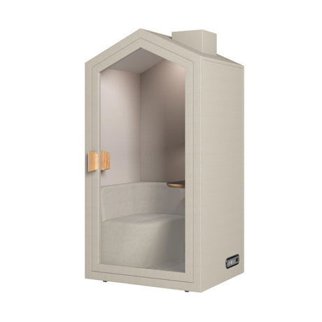 The product is an acoustic meeting pod designed for private conversations or focused work. It features a cottage-like design with a light, neutral color scheme and a glass door. Inside, there is a comfortable seating area and a small wooden shelf, creating a cozy and functional space for meetings or calls.