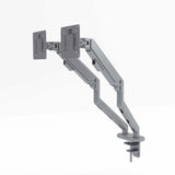 The product is a dual monitor arm designed for ergonomic use in an office setting. It features two adjustable arms that can hold two monitors, allowing for flexible positioning. The design is sleek and modern, with a gray finish, and it includes a mounting base for easy installation on a desk.
