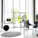 The image features an ergonomic seating ball, designed to promote better posture and active sitting. The setting includes a modern office space with large windows, a desk with a computer, and a stylish chair, creating a bright and inviting atmosphere. The seating ball is positioned on the floor, complementing the contemporary decor.