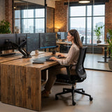 The image features an ergonomic office chair, likely from the "Glory" model line. It shows a woman working at a wooden desk with multiple monitors displaying data, in a modern office setting with large windows and greenery in the background. The chair is designed for comfort and support, suitable for long hours of work.