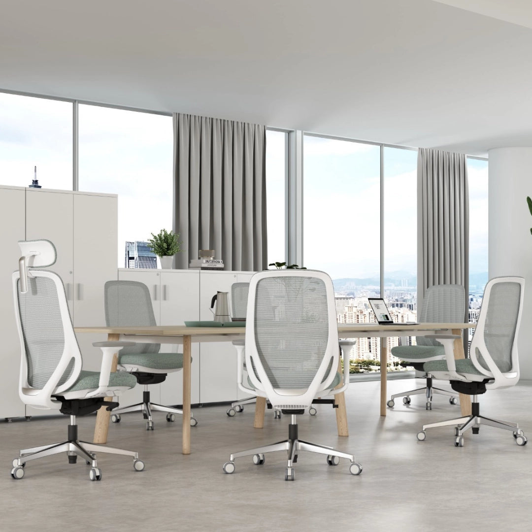 The product is an ergonomic office chair, specifically the "Glory" model. The image shows a modern office setting with several of these chairs arranged around a wooden table. The chairs feature a sleek design with mesh backs and cushioned seats, providing a contemporary and comfortable workspace. Large windows in the background offer a view of the city, enhancing the office