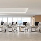 The image features ergonomic office chairs arranged in a modern office setting. The chairs have a sleek design with mesh backs and headrests, promoting comfort and support for long hours of work. The workspace includes desks and computer monitors, with large windows providing a view of the city.