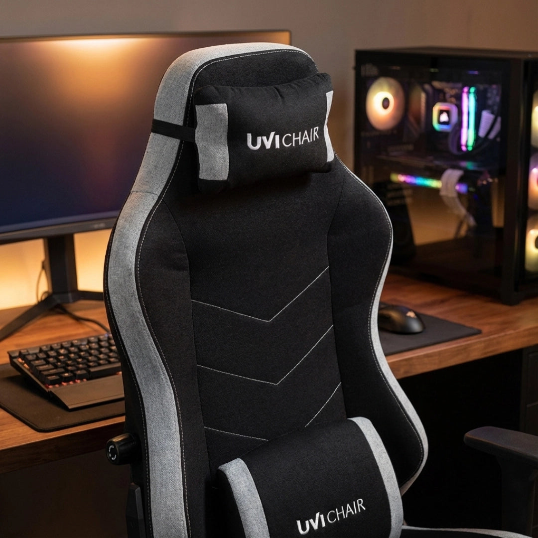 The product is an ergonomic office chair designed for gaming, specifically the UVI Alpha model. The image shows a sleek black and gray chair with a high back, featuring a headrest and lumbar support, set against a modern workspace with a computer monitor and a gaming PC in the background.