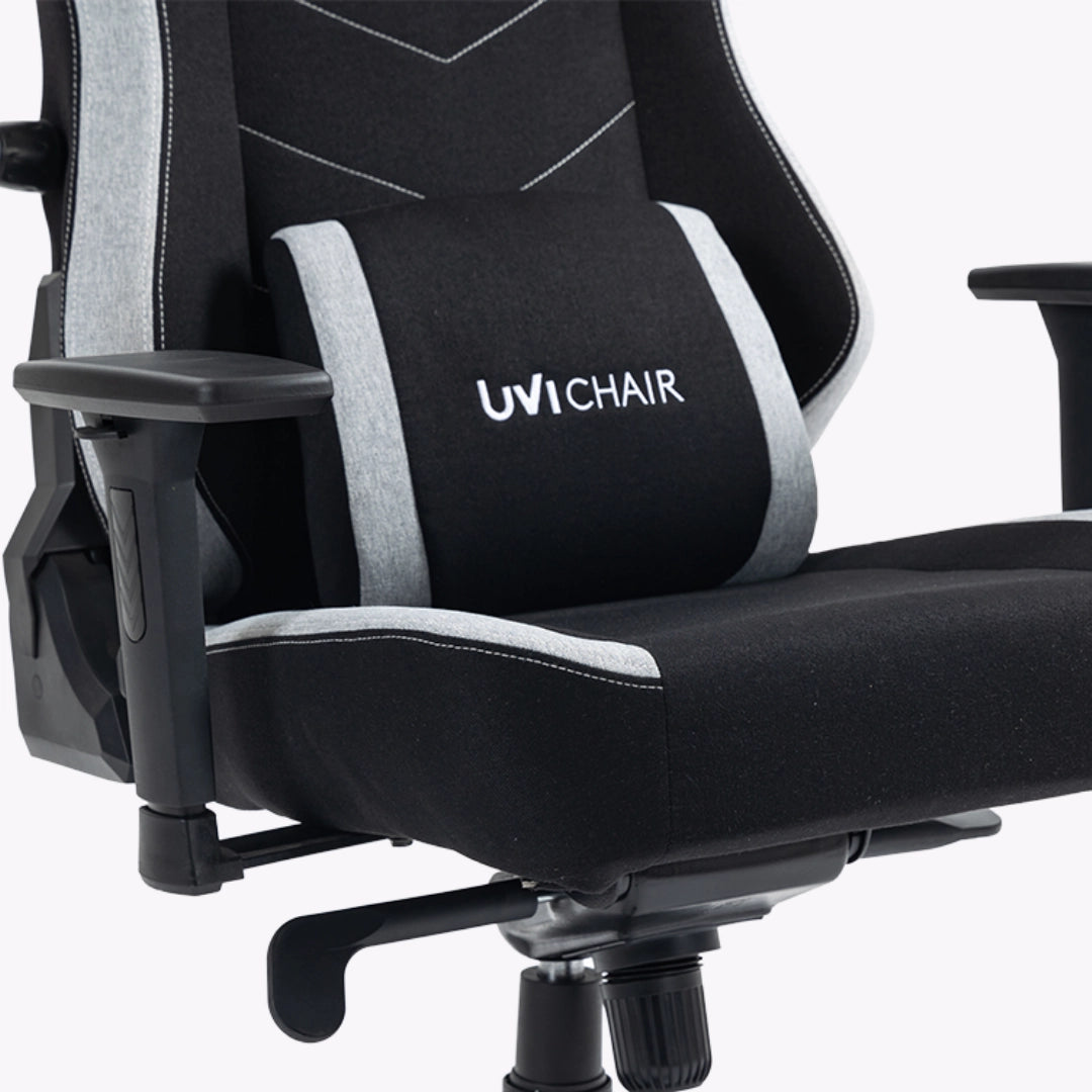 The product is an ergonomic office chair designed for gaming, specifically the UVI Alpha model. The image shows a close-up of the chair's seat and backrest, featuring a sleek black fabric with gray accents. The chair includes adjustable armrests and a lumbar support cushion, enhancing comfort for extended use. The UVI Chair logo is prominently displayed on the