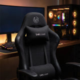 The product is an ergonomic office chair designed for gaming, specifically the UviChair model in black. The image showcases the chair's sleek design, featuring a high backrest, a supportive neck pillow, and a modern aesthetic. In the background, there is a gaming setup with a keyboard and a colorful PC case, enhancing the gaming atmosphere.