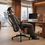 The product is an ergonomic office chair, specifically the UVI Focus model. The image shows a man in a suit comfortably reclining in the chair, which features a modern design with a supportive backrest. The setting appears to be a stylish office with wooden accents and a computer desk in the background.