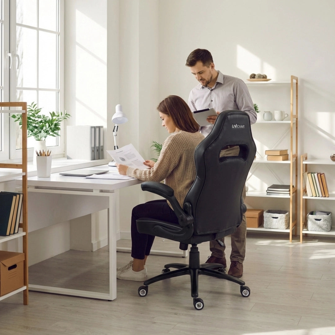 The image features an ergonomic office chair from the brand UVIOMAR. It shows a woman sitting at a desk, reviewing documents, while a man stands nearby holding a tablet. The chair is designed for comfort and support, with a sleek black finish and adjustable features, set in a bright, modern office environment.