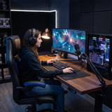 The image features an ergonomic gaming chair, specifically the UVI Storm Blue model. It showcases a person seated at a gaming setup, complete with a curved monitor displaying a space-themed game, a mechanical keyboard, and a microphone. The chair is designed with blue accents, and the environment has a modern gaming aesthetic with ambient lighting and a stylish desk.
