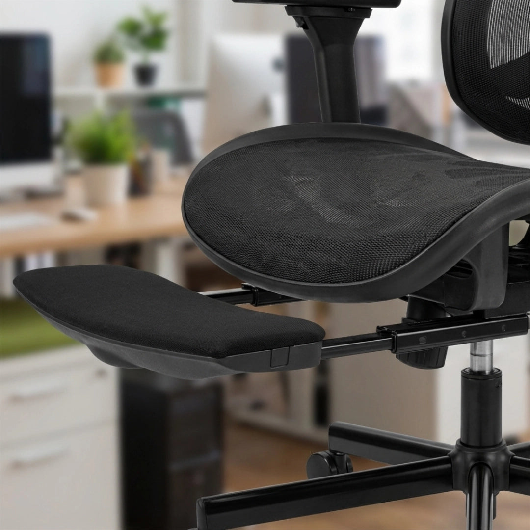 The product is an ergonomic office chair, specifically the UVI Focus Pro model. The image shows a black chair with a mesh seat and an adjustable armrest. The background features a modern office setting with plants and a desk, indicating a professional environment.