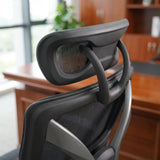 The product is an ergonomic office chair, specifically the UVI Focus Pro model. The image shows the backrest of the chair, featuring a sleek design with a mesh material for breathability and support. The chair has a modern aesthetic, complemented by a sturdy frame and a minimalist style, set against a backdrop of a wooden office environment.