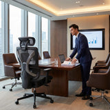 The image features an ergonomic office chair, specifically the UVI Focus Pro model. It is positioned in a modern conference room setting, showcasing a sleek design with a mesh back for breathability. A man in a suit is seen preparing documents at a conference table, with a presentation screen displaying graphs in the background.