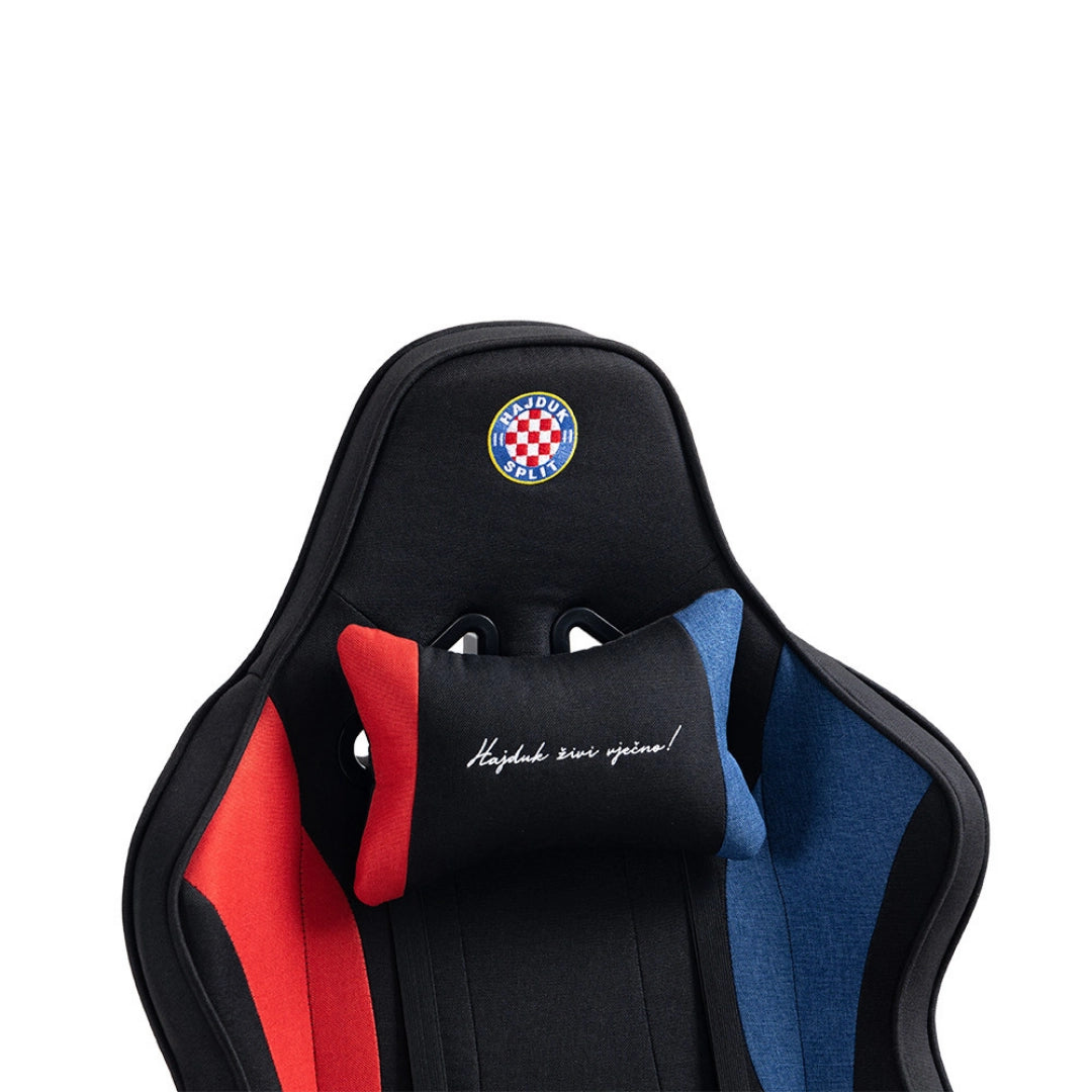 The product is an ergonomic gaming chair, specifically the UVI X Hajduk model. The chair features a sleek design with a black base and colorful accents in red and blue. It includes a headrest pillow that has a slogan in Croatian, showcasing the Hajduk Split football club logo prominently on the top.